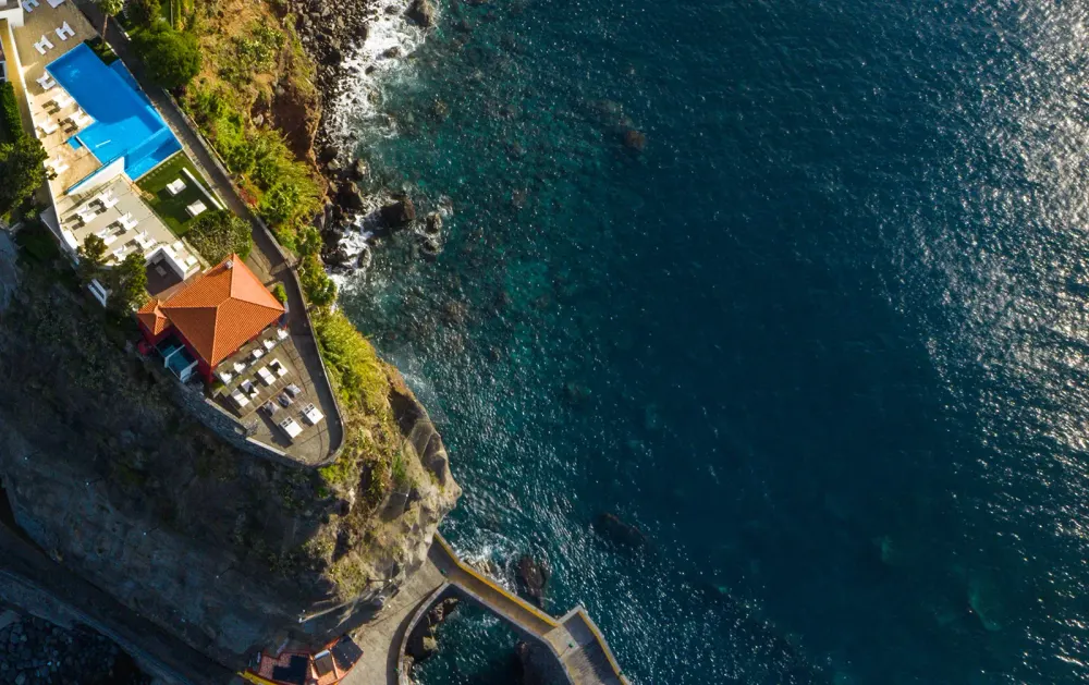 Cliff-edge infinity pool of Estalagem da Ponta do Sol above the village and the Atlantic, Madeira