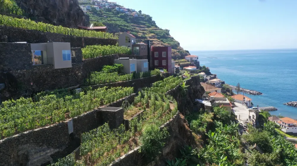 Stone-and-timber houses stepping down the farming terraces at Socalco Nature above Calheta, Madeira